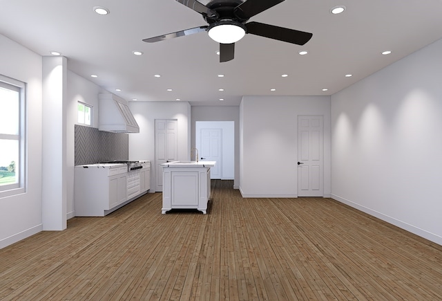 kitchen featuring light hardwood / wood-style flooring, white cabinets, a kitchen island, and a wealth of natural light