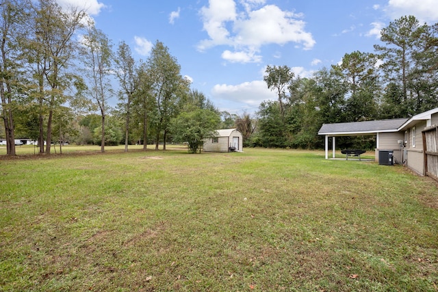 view of yard featuring central AC unit, a storage unit, and a carport