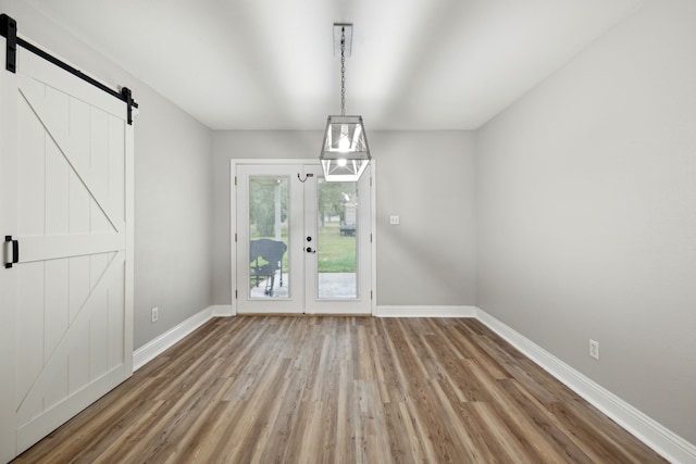 unfurnished dining area with a barn door and hardwood / wood-style flooring