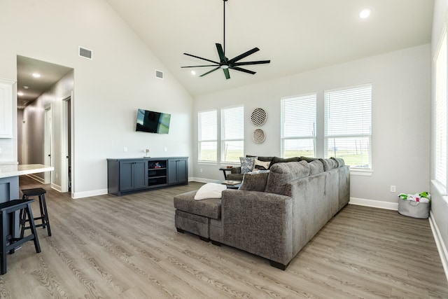 living room with light hardwood / wood-style floors, high vaulted ceiling, and ceiling fan