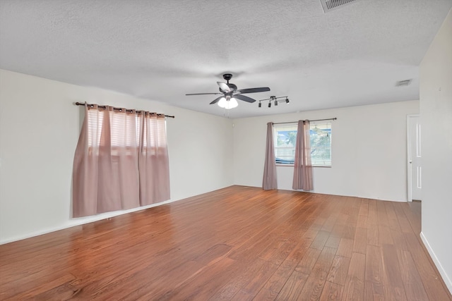 empty room with ceiling fan, wood-type flooring, and a textured ceiling