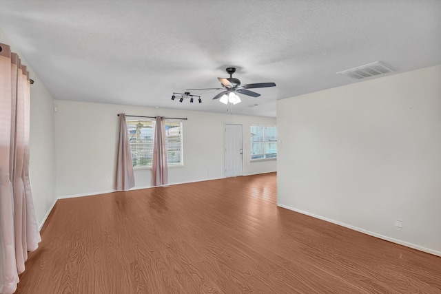 unfurnished room with a textured ceiling, wood-type flooring, and ceiling fan