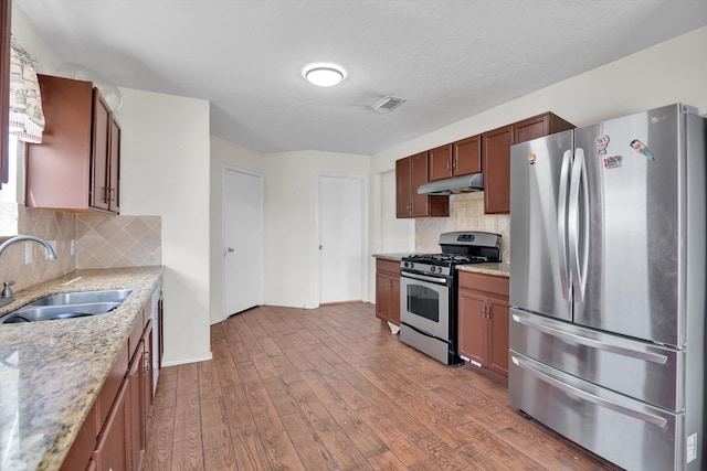 kitchen with appliances with stainless steel finishes, light hardwood / wood-style flooring, tasteful backsplash, and sink