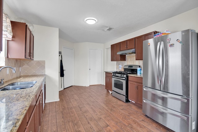 kitchen featuring appliances with stainless steel finishes, light hardwood / wood-style flooring, decorative backsplash, and sink