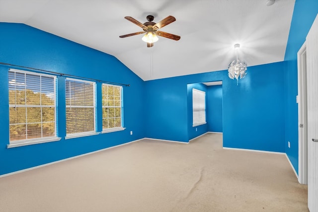 carpeted empty room featuring vaulted ceiling and ceiling fan with notable chandelier