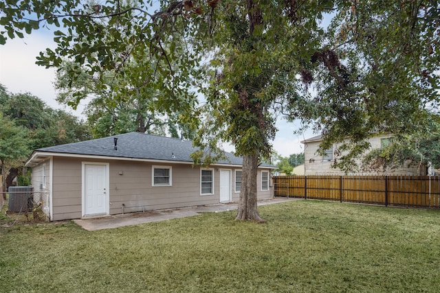 rear view of house with central AC and a yard