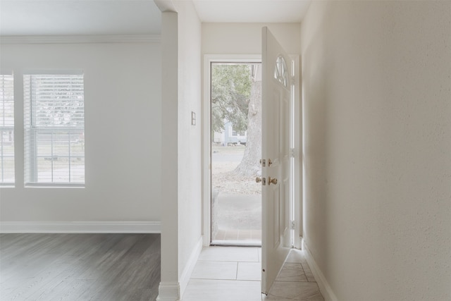 doorway featuring plenty of natural light, light wood-type flooring, and crown molding