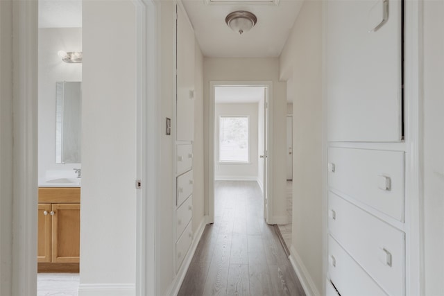 hallway with sink and light hardwood / wood-style flooring