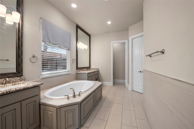 bathroom with tile patterned floors, a washtub, and vanity