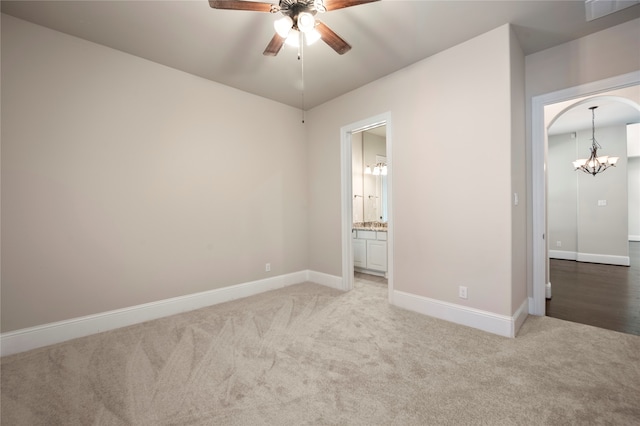 unfurnished bedroom with ensuite bathroom, carpet, and ceiling fan with notable chandelier