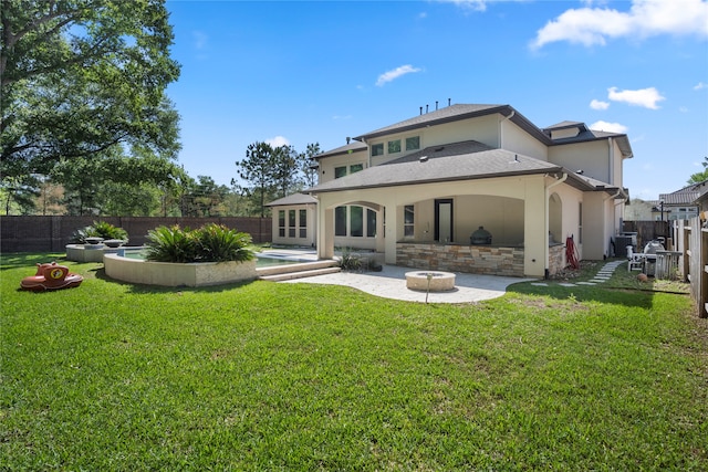 rear view of house with a yard, a patio, and a fire pit