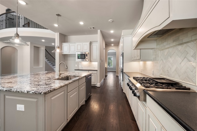 kitchen featuring pendant lighting, a kitchen island with sink, white cabinets, sink, and stainless steel appliances