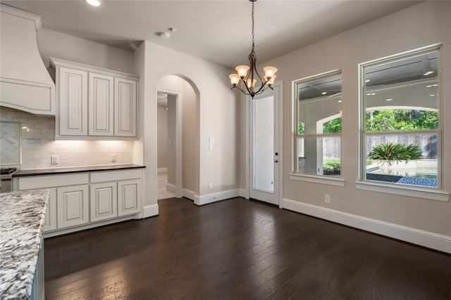 kitchen featuring decorative backsplash, custom range hood, dark wood-type flooring, pendant lighting, and white cabinetry