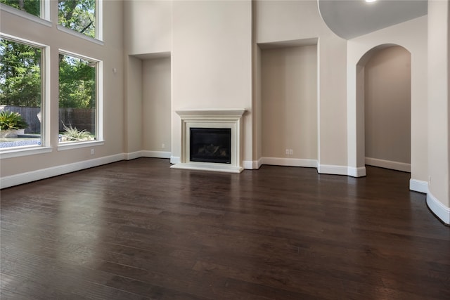 unfurnished living room featuring a towering ceiling and dark hardwood / wood-style floors