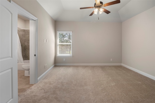 carpeted spare room featuring vaulted ceiling and ceiling fan