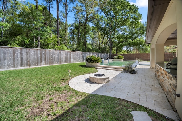 view of yard with a fire pit, an outdoor kitchen, a fenced in pool, and a patio