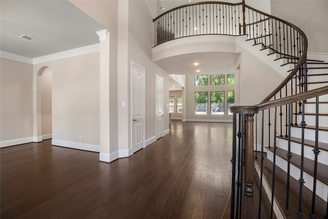 foyer entrance with a towering ceiling, dark hardwood / wood-style floors, and crown molding