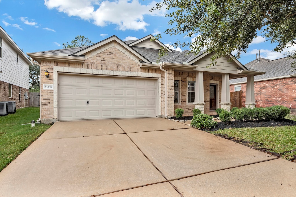 view of front of home featuring a garage, central AC, and a front yard