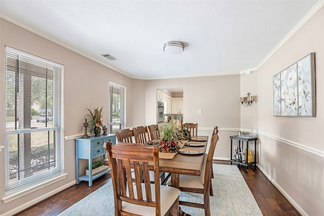 dining space with ornamental molding, a healthy amount of sunlight, and dark hardwood / wood-style flooring