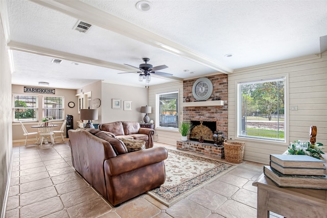 tiled living room with ceiling fan, a healthy amount of sunlight, a textured ceiling, and a brick fireplace