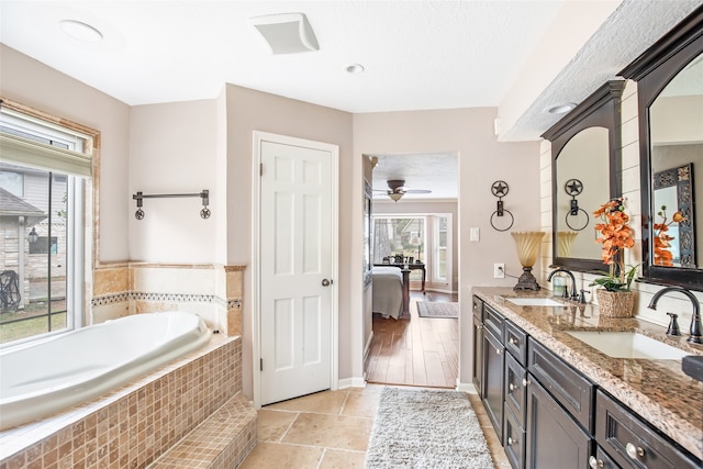 bathroom with vanity, hardwood / wood-style floors, tiled tub, and ceiling fan