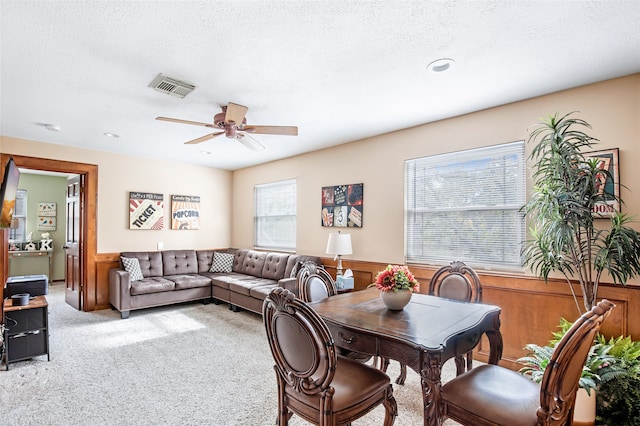 dining area with a textured ceiling, light colored carpet, and plenty of natural light