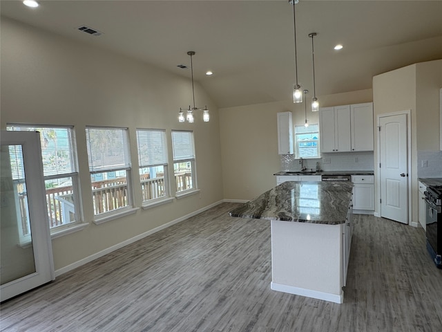 kitchen with a kitchen island, decorative light fixtures, white cabinetry, dark stone countertops, and decorative backsplash