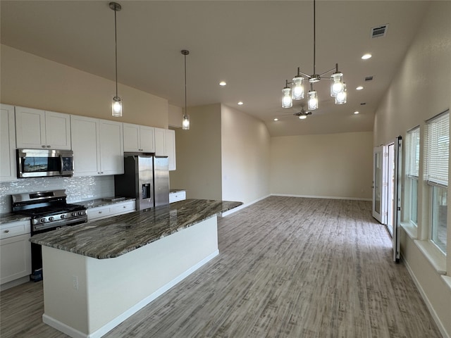 kitchen with stainless steel appliances, pendant lighting, white cabinets, and tasteful backsplash