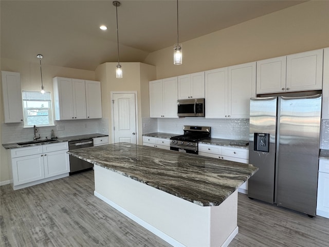 kitchen with lofted ceiling, a kitchen island, sink, appliances with stainless steel finishes, and white cabinets