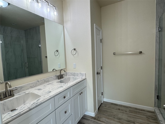 bathroom with a shower with shower door, hardwood / wood-style flooring, and vanity