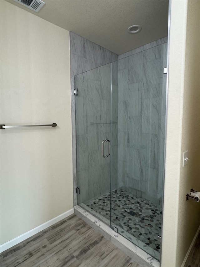 bathroom with hardwood / wood-style flooring and an enclosed shower