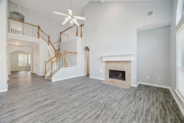 unfurnished living room with hardwood / wood-style flooring, ceiling fan, a fireplace, and a high ceiling