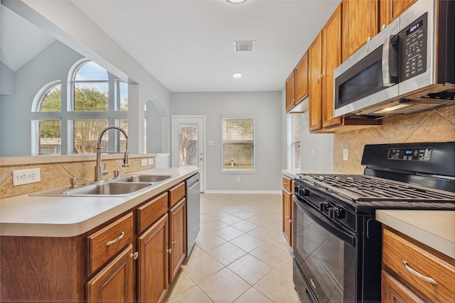 kitchen featuring stainless steel appliances, a healthy amount of sunlight, sink, and light tile patterned floors