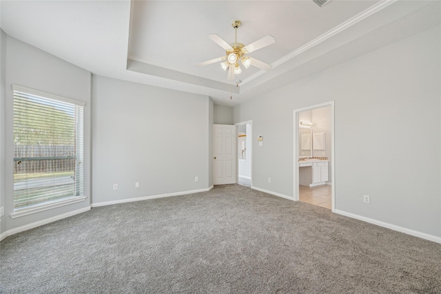 unfurnished bedroom with light carpet, a tray ceiling, ensuite bath, and ceiling fan