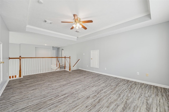 unfurnished room featuring crown molding, ceiling fan, wood-type flooring, and a tray ceiling