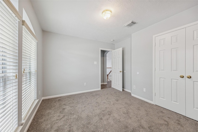 unfurnished bedroom featuring a textured ceiling and carpet