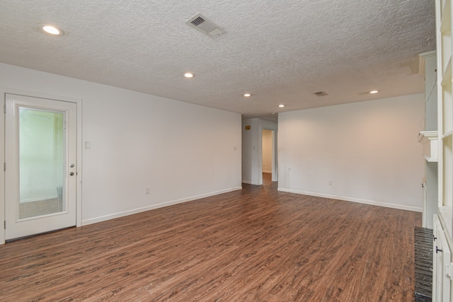 empty room with dark hardwood / wood-style floors, a textured ceiling, and a fireplace