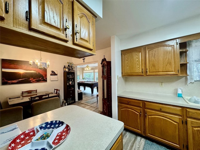 kitchen featuring pool table, ceiling fan with notable chandelier, light wood-type flooring, and pendant lighting