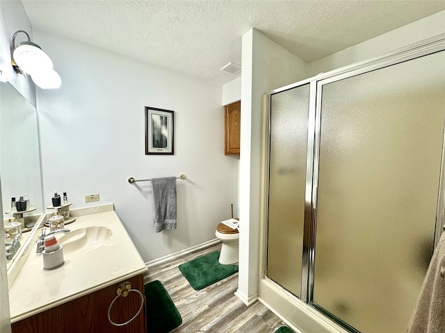 bathroom with toilet, a shower with shower door, hardwood / wood-style floors, and vanity