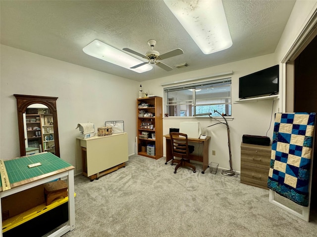 carpeted office featuring a textured ceiling and ceiling fan