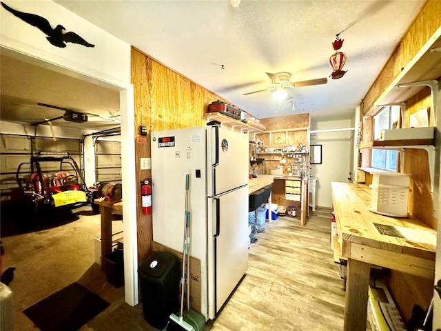 kitchen with ceiling fan, white refrigerator, light hardwood / wood-style flooring, wood walls, and butcher block countertops