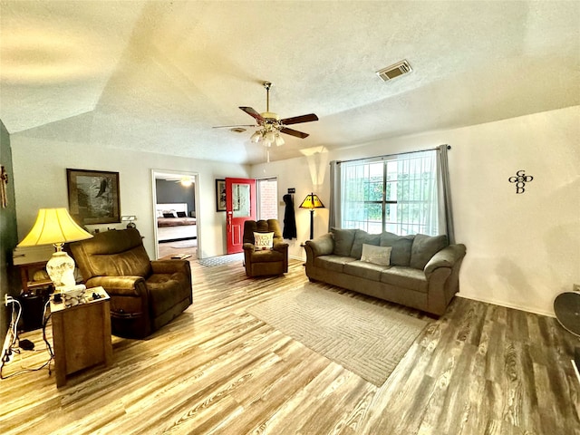 living room with ceiling fan, a textured ceiling, wood-type flooring, and vaulted ceiling