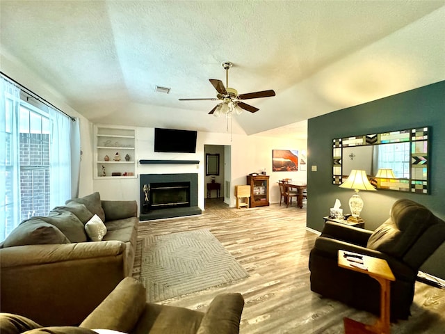 living room featuring light hardwood / wood-style floors, a textured ceiling, ceiling fan, and vaulted ceiling