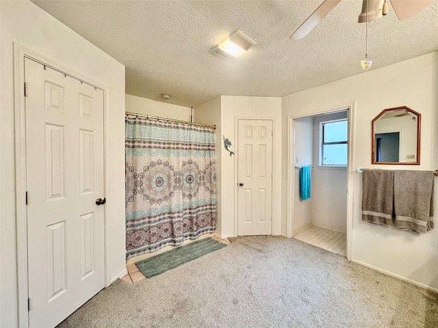 bathroom with a textured ceiling, walk in shower, and ceiling fan