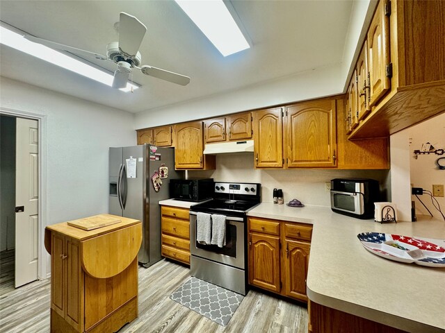 kitchen featuring kitchen peninsula, appliances with stainless steel finishes, light hardwood / wood-style flooring, and ceiling fan