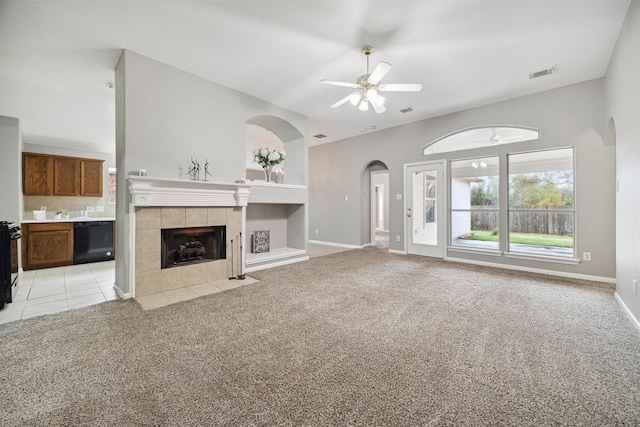 unfurnished living room with light carpet, a tiled fireplace, and ceiling fan