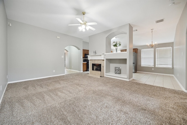 unfurnished living room featuring light colored carpet, ceiling fan with notable chandelier, and a fireplace