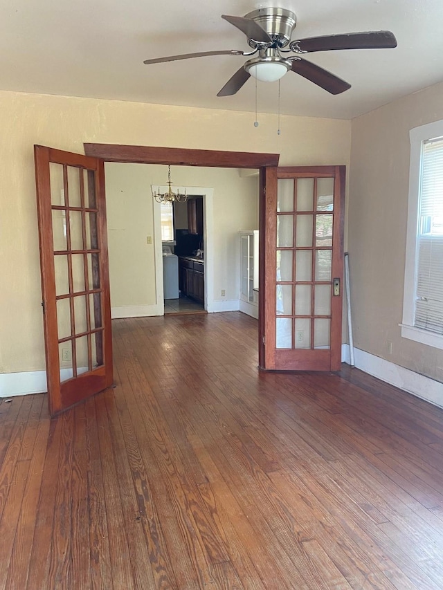 unfurnished room featuring dark wood finished floors, baseboards, and ceiling fan with notable chandelier