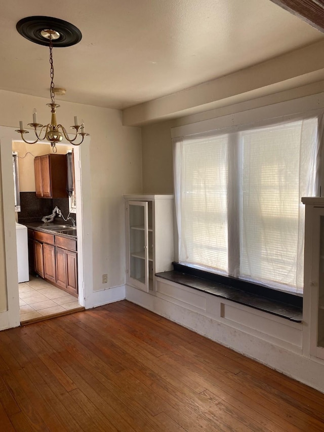 unfurnished dining area featuring light wood-type flooring, baseboards, and a chandelier