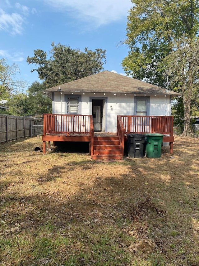 back of property featuring a deck, a yard, and fence